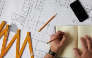 a man writing on construction papers and blue prints