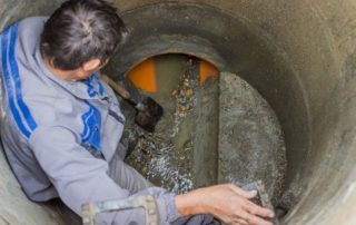 man standing in a sewer working on the repair